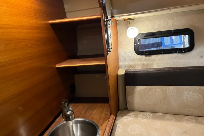 Slide: The Image of 2017 Ranger Tugs R-23 cabin interior with wooden shelves, sink, and cushioned seating. - 11
