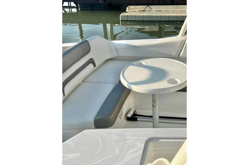 Slide: The Image of 2022 World Cat 230 DC boat interior with seating and round table by the water. - 12
