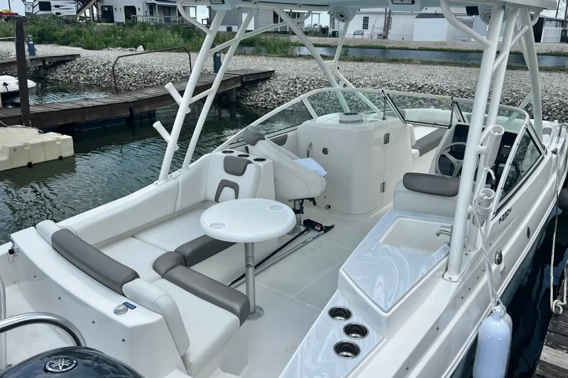 Slide: The Image of 2022 World Cat 230 DC boat interior with seating and helm, docked by the water. - 6