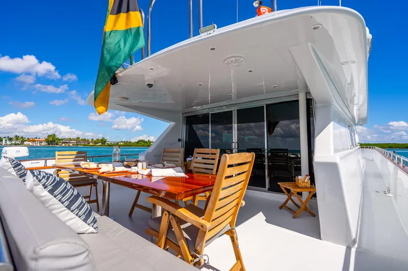 Slide: The Image of Luxurious 1991 Maiora Planning yacht deck with dining area, ocean view, and vibrant flag. - 4