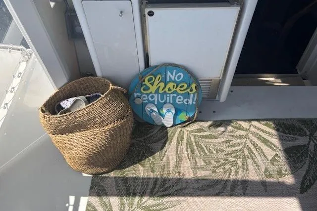 Slide: The Image of 1996 Carver 355 Aft Cabin Motor Yacht interior with "No Shoes Required" sign and woven basket. - 7