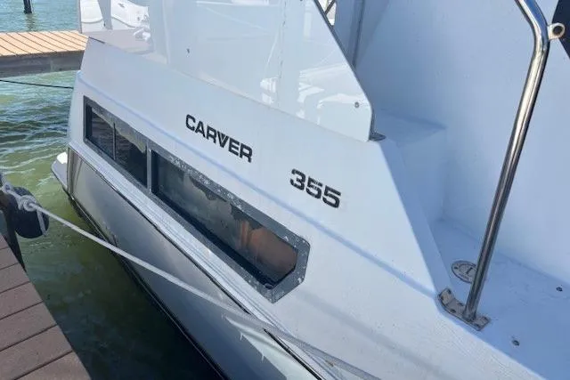 Slide: The Image of 1996 Carver 355 Aft Cabin Motor Yacht docked, showcasing sleek design and branding. - 4