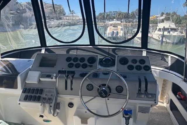 Slide: The Image of 1996 Carver 355 Aft Cabin Motor Yacht helm with steering wheel and control panel. - 5