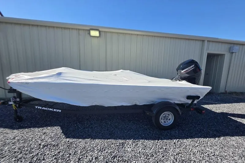 Slide: The Image of 2026 Tracker Pro 170 boat covered, on trailer, beside metal building. - 2