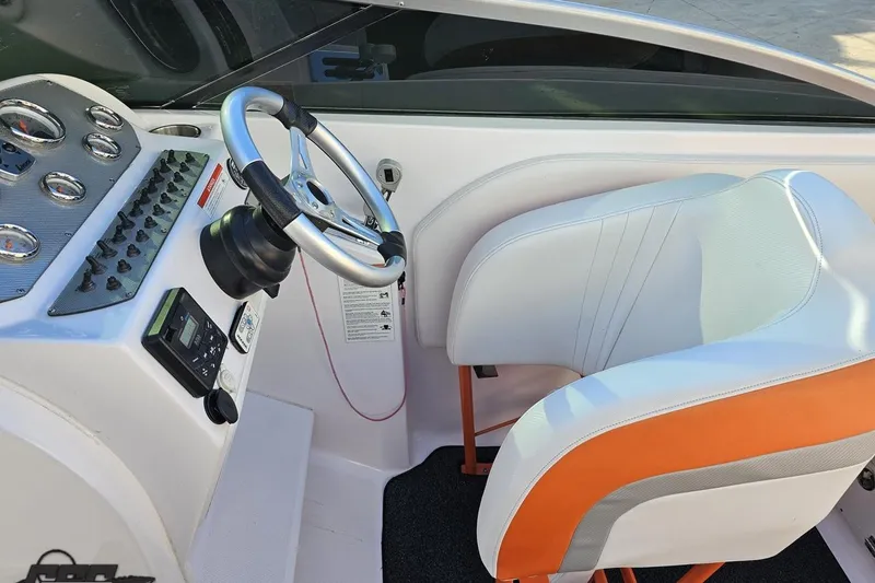 Slide: The Image of 2016 Baja 247 Islander boat cockpit with steering wheel and orange-accented seat. - 63