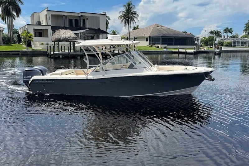 Slide: The Image of 2020 Grady-White Freedom 285 boat on a calm waterfront, with modern homes in the background. - 10
