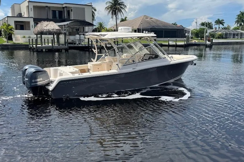 Slide: The Image of 2020 Grady-White Freedom 285 boat on water, near waterfront homes and palm trees. - 12