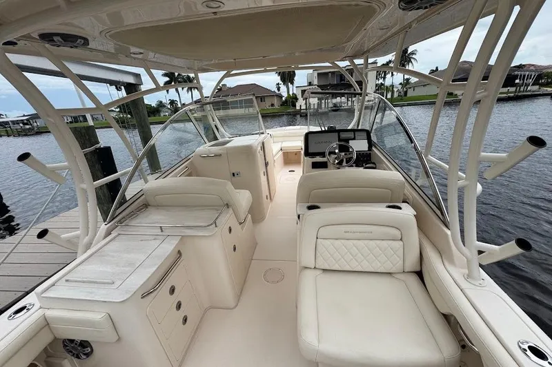 Slide: The Image of 2020 Grady-White Freedom 285 boat interior with luxurious seating and helm, docked by the water. - 15