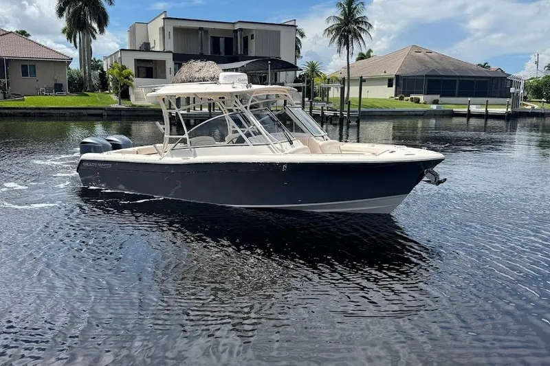 Slide: The Image of 2020 Grady-White Freedom 285 boat on a calm waterfront, with modern homes in the background. - 9