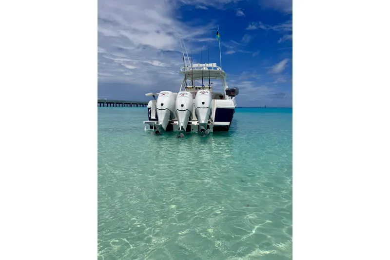 Slide: The Image of 2006 Intrepid 377 Walkaround boat in clear turquoise water, under a partly cloudy sky. - 2