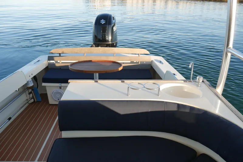 Slide: The Image of 2023 Seaway 24 Seafarer boat interior with seating, table, and sink on calm water. - 14