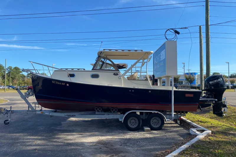 Slide: The Image of 2023 Seaway 24 Seafarer boat on calm water near a wooden dock. - 2