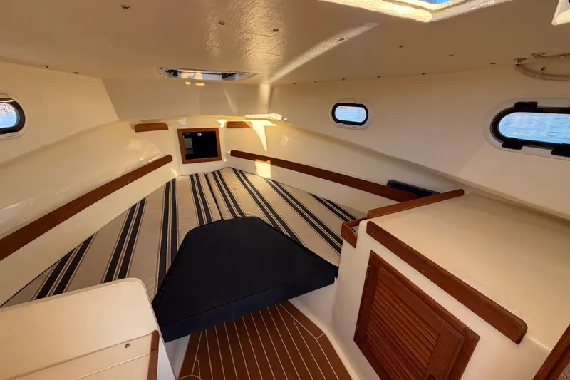 Slide: The Image of 2023 Seaway 24 Seafarer cabin interior with striped cushions and wooden accents. - 22