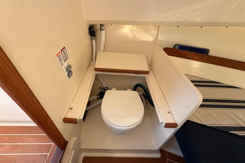 Slide: The Image of 2023 Seaway 24 Seafarer boat interior with compact marine toilet and striped bedding. - 23