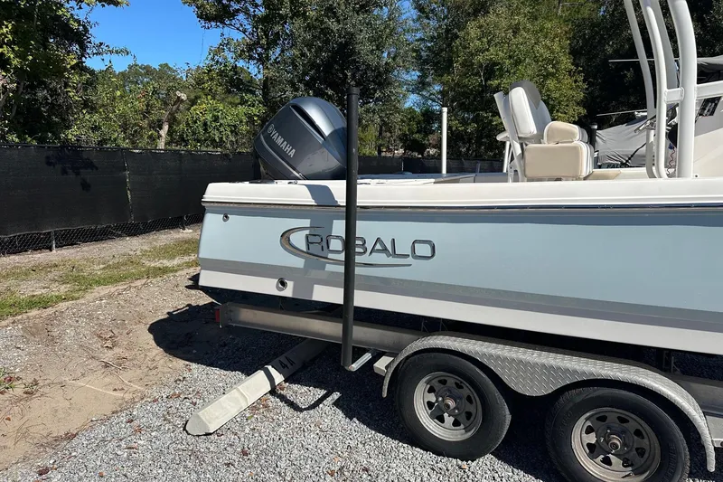 Slide: The Image of 2020 Robalo 246 Cayman boat on trailer with Yamaha engine, parked outdoors. - 2