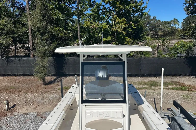 Slide: The Image of 2020 Robalo 246 Cayman boat on trailer, surrounded by trees and fencing. - 6