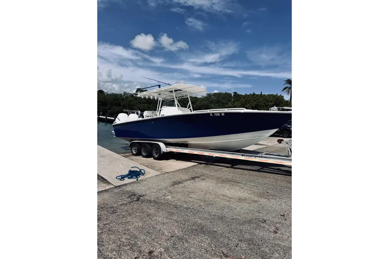 The Image of 2005 Jupiter 31 boat on trailer at dock, under clear blue sky. - 0