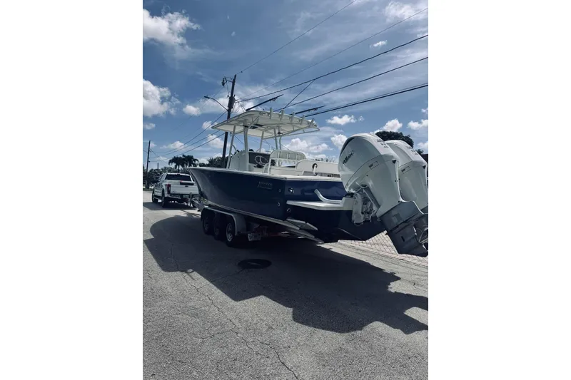 Slide: The Image of 2005 Jupiter 31 boat on trailer with dual engines under a clear sky. - 10