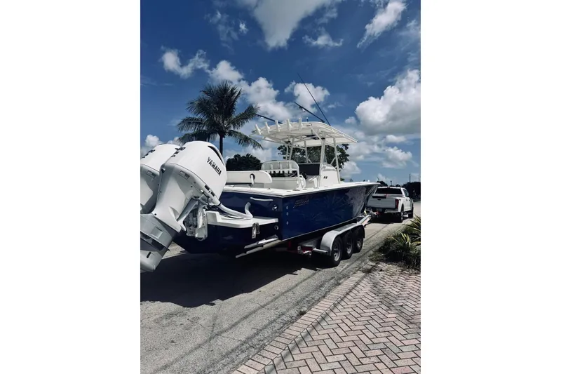 Slide: The Image of 2005 Jupiter 31 boat on trailer, parked near palm tree under blue sky. - 13