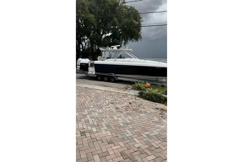 Slide: The Image of 2005 Jupiter 31 boat on trailer, parked on brick driveway, with overcast sky. - 18