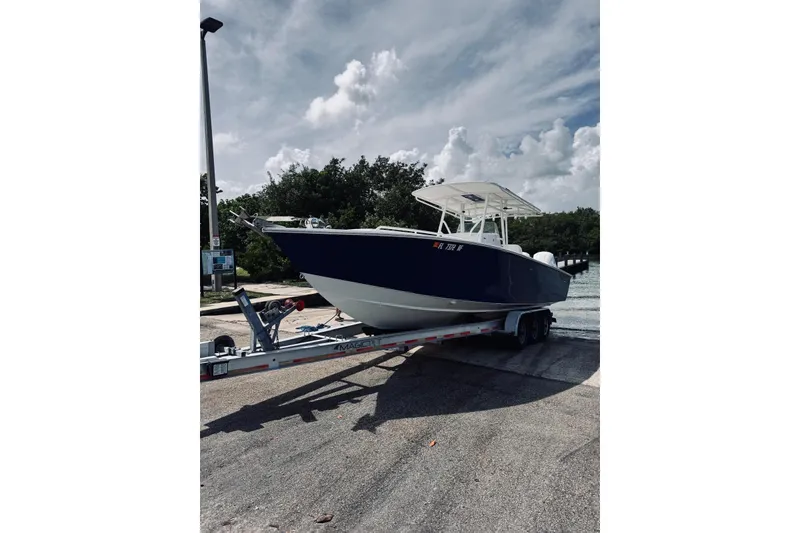 Slide: The Image of 2005 Jupiter 31 boat on trailer, parked near water under cloudy sky. - 20