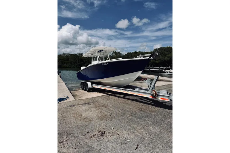 Slide: The Image of 2005 Jupiter 31 boat on trailer by waterfront under blue sky. - 3