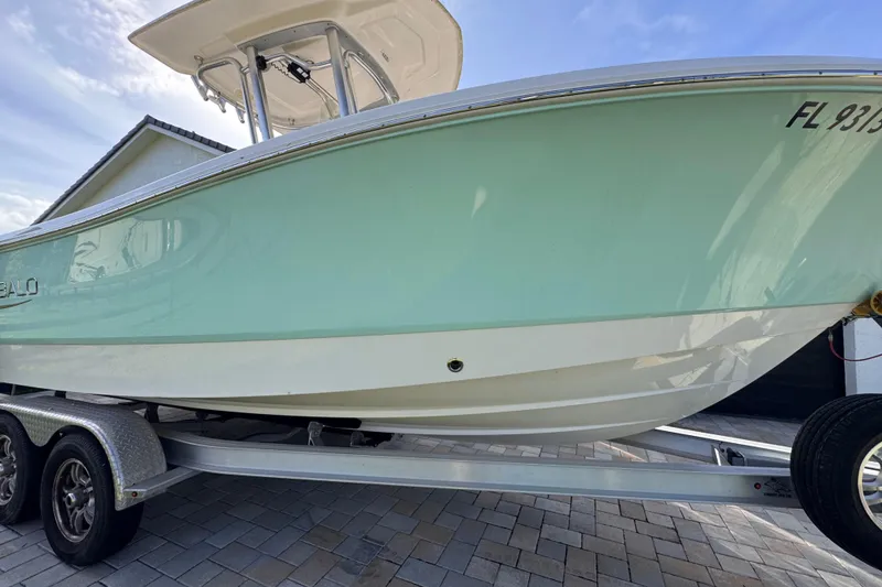 Slide: The Image of 2022 Robalo R230 Center Console boat on trailer, light blue hull, parked on paved driveway. - 14