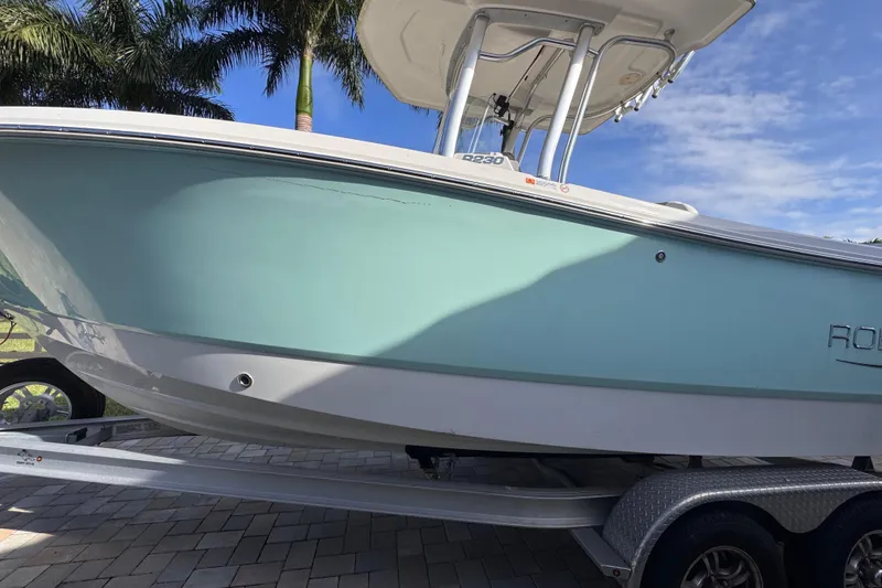Slide: The Image of 2022 Robalo R230 Center Console boat on trailer, palm trees in background. - 3