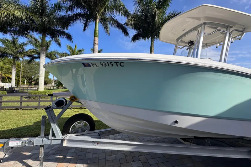 Slide: The Image of 2022 Robalo R230 Center Console boat on trailer, surrounded by palm trees. - 60