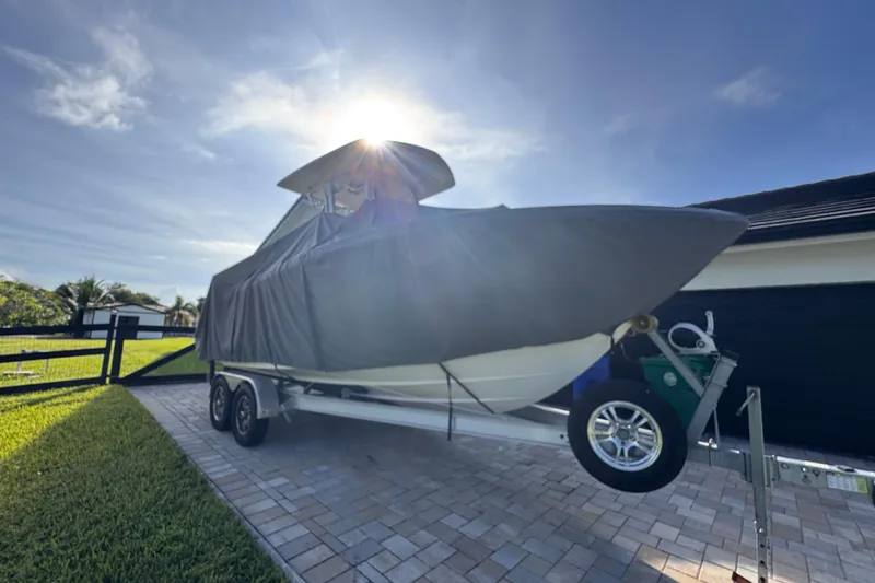 Slide: The Image of 2022 Robalo R230 Center Console boat covered on trailer in driveway, sunny day. - 61