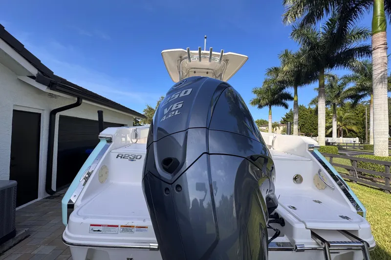 Slide: The Image of 2022 Robalo R230 Center Console boat with powerful V6 engine, parked near palm trees. - 8