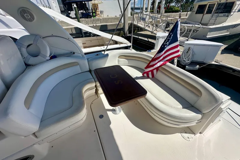 Slide: The Image of 2008 Sea Ray 340 Sundancer boat with American flag, featuring white seating and a wooden table. - 7