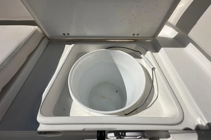 Slide: The Image of 2024 Sea Hunt Ultra 219 boat storage compartment with a white bucket inside. - 17