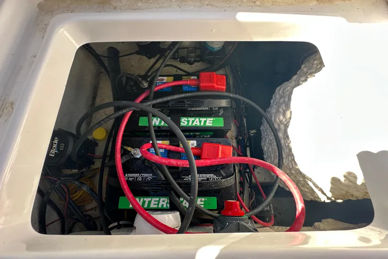 Slide: The Image of 2024 Sea Hunt Ultra 219 boat battery compartment with Interstate batteries and wiring. - 25