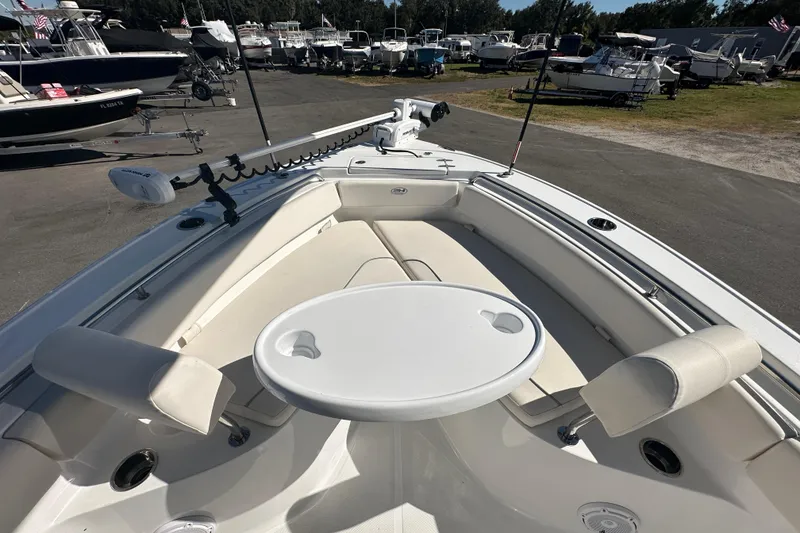 Slide: The Image of 2024 Sea Hunt Ultra 219 boat interior with seating and table, docked among other boats. - 57