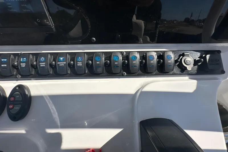 Slide: The Image of Control panel of 2024 Sea Hunt Ultra 219 boat with various switches and 12V outlet. - 73