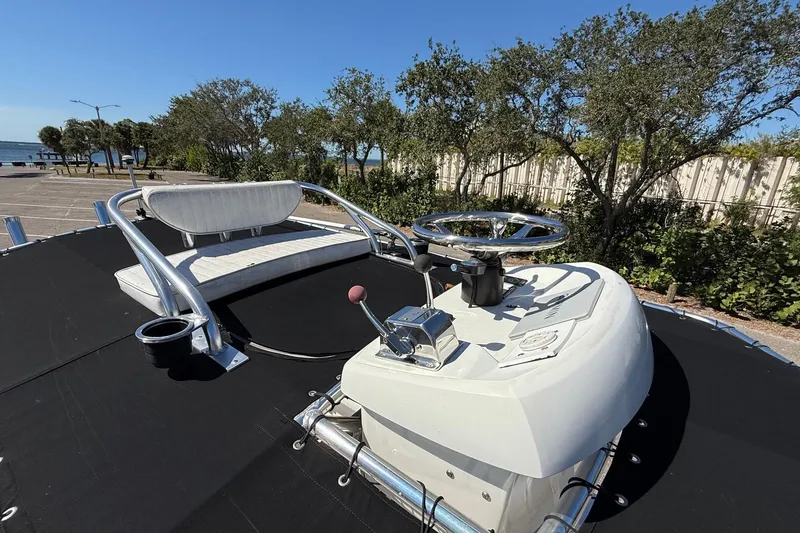Slide: The Image of 2022 Parker 2100 Special Edition boat helm with steering wheel and seating, docked near trees. - 17