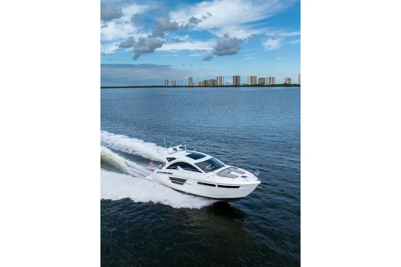 Slide: The Image of 2022 Cruisers Yachts 54 Cantius cruising on open water under a blue sky. - 13