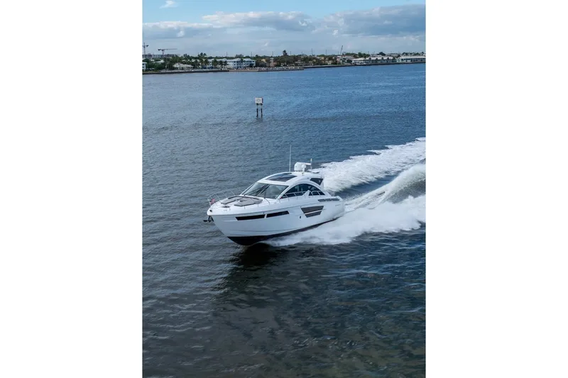 Slide: The Image of 2022 Cruisers Yachts 54 Cantius cruising on open water under a cloudy sky. - 14