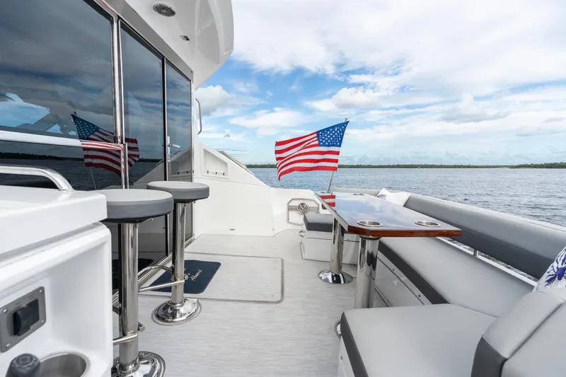 Slide: The Image of 2022 Cruisers Yachts 54 Cantius deck with seating, table, and American flag. - 22