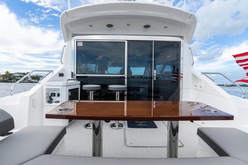 Slide: The Image of 2022 Cruisers Yachts 54 Cantius aft deck with seating and table, overlooking water. - 21