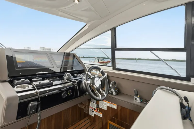 Slide: The Image of 2022 Cruisers Yachts 54 Cantius helm with modern navigation displays and scenic water view. - 29