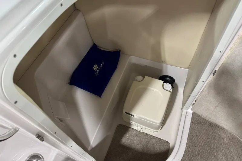 Slide: The Image of 2006 Four Winns 244 Funship interior storage with portable toilet and branded cushion. - 12