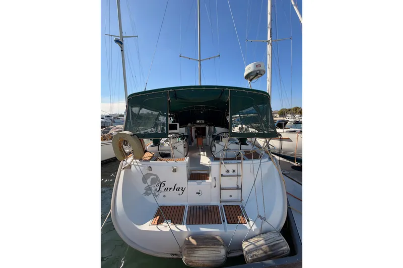 Slide: The Image of 2003 Beneteau Oceanis Clipper 473 sailboat docked, rear view with green canopy. - 2