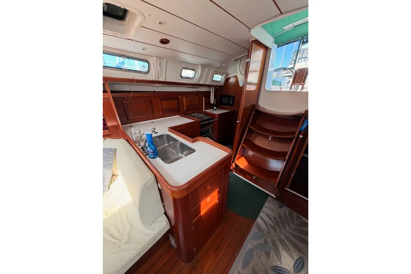 Slide: The Image of Interior of 2003 Beneteau Oceanis Clipper 473 yacht, featuring a cozy kitchen and wooden cabinetry. - 33
