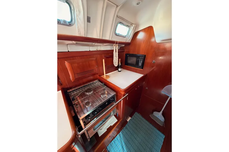 Slide: The Image of 2003 Beneteau Oceanis Clipper 473 yacht kitchen with stove, microwave, and wooden cabinetry. - 34