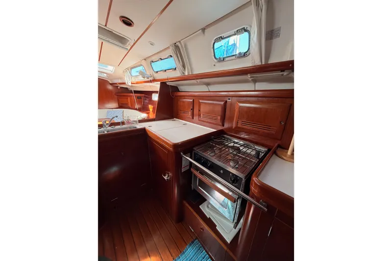 Slide: The Image of Interior of 2003 Beneteau Oceanis Clipper 473 yacht, featuring a compact kitchen area. - 35