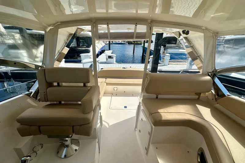 Slide: The Image of Interior of 2015 Pursuit SC 365i Sport Coupe with beige seating and marina view. - 14