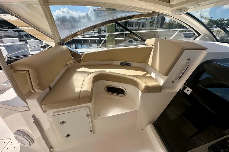 Slide: The Image of 2015 Pursuit SC 365i Sport Coupe interior with beige seating and marina view. - 15