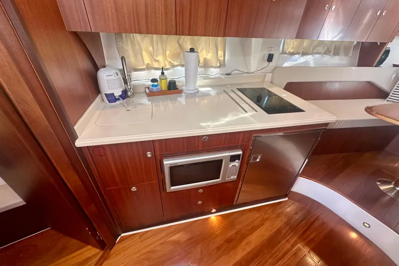 Slide: The Image of 2015 Pursuit SC 365i Sport Coupe galley with microwave, cooktop, and wood cabinetry. - 23